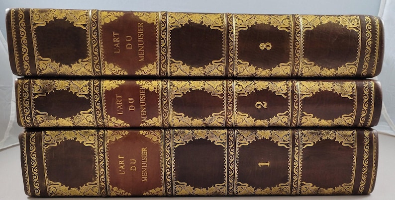 Three gilt-tooled leather volumes of L'Art du Menuisier, photographed in the shop.